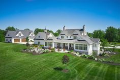 an aerial view of a large white house in the middle of a green field with trees and shrubs