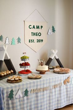 a table topped with cakes and desserts next to a sign that says camp theeo