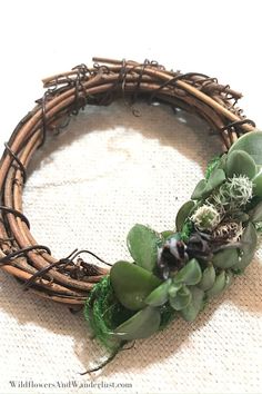 a close up of a wreath with succulents and leaves on the side