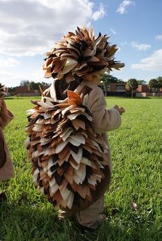 two children dressed up in costumes made out of books, standing in the grass with their hands together