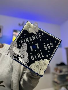 a woman holding up a black and white graduation cap that says finance it's girl