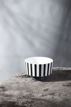 a black and white striped bowl sitting on top of a wooden table next to a gray wall