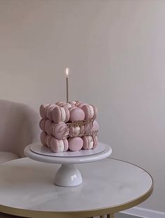 a white cake sitting on top of a table with a lit candle in the middle