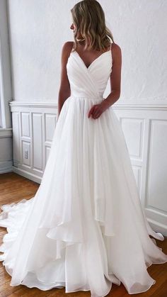 a woman in a white wedding dress standing on a wooden floor