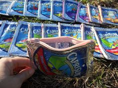 someone is picking up an empty cup from the ground in front of several packets of chips