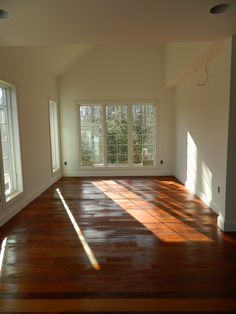 an empty room with hard wood floors and large windows