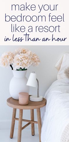 a bedroom with white walls and flowers in a vase on the end table next to a bed