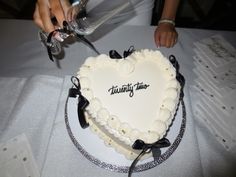 a heart - shaped cake is being cut by someone at a table with wine glasses