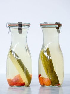 two glass jars filled with pickles and oranges