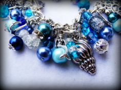 This is a handmade beaded charm bracelet full of wonderful Tibetan silver and silver plated charms, glass beads and pearls inspired by Sirens of the sea. The charms are sea shells, mermaids, turtles, dolphins, starfish and other sea inspired themes with a beautiful dragonfly clasp. This is 7.5 inches long but can be made longer if required :)  In mythology, sirens were seen as beautiful and dangerous creatures depicted as mermaids who used to lure sailors into rocks with their enchanting singing Handmade Silver Beaded Bracelets Ocean-inspired, Ocean-inspired Silver Beaded Bracelets, Silver Beaded Ocean-inspired Bracelets, Handmade Silver Charm Bracelet For Beach, Ocean-inspired Silver Beaded Jewelry, Silver Beaded Ocean-inspired Jewelry, Dangerous Creatures, Beautiful Dragonfly, Beaded Charm Bracelet