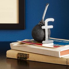 a bookend with a bird figurine sitting on top of books in front of a blue wall