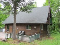 a log cabin sits in the middle of a wooded area with stairs leading up to it