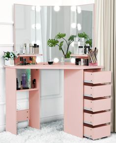 a pink vanity table with drawers and lights