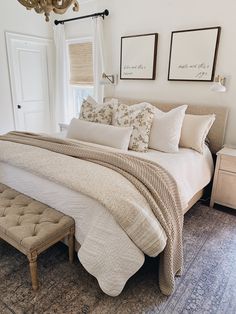 a bed with white sheets and pillows in a bedroom next to a chandelier