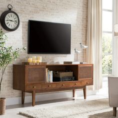 a living room with a large flat screen tv mounted on the wall above a wooden entertainment center