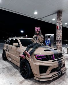 a man sitting on the hood of a beige jeep parked in front of a gas station