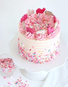 a white cake with pink frosting and sprinkles