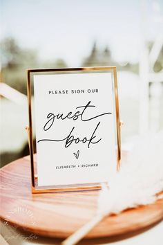 a guest book sitting on top of a wooden table next to a white sign that says guest book