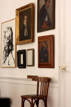 a chair sitting in front of a wall with pictures hanging on it's side