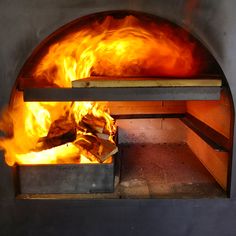 a fire burning inside of an oven filled with lots of hot coal and flames on both sides