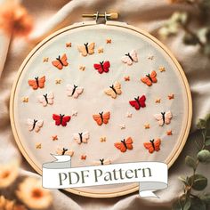 an embroidery project with orange and red butterflies on white fabric, surrounded by yellow flowers