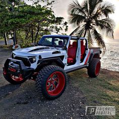 a white and red jeep parked next to the ocean