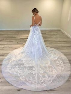 a woman in a white wedding dress standing on the floor looking down at her back