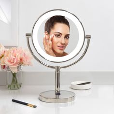 a woman's face is reflected in a round mirror next to a flower vase