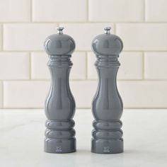 two gray salt and pepper shakers sitting on top of a counter