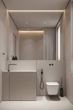 a bathroom with a white toilet sitting next to a sink under a mirror and lights