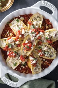 a white casserole dish filled with ravioli and cheese