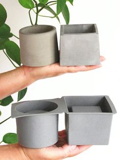 two gray pots are held in the palm of a person's hand