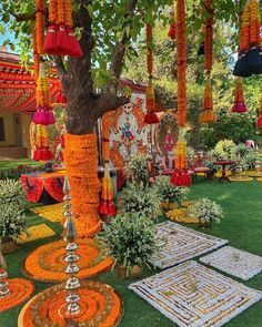 an outdoor area with orange and white decorations on the grass, trees, and rugs