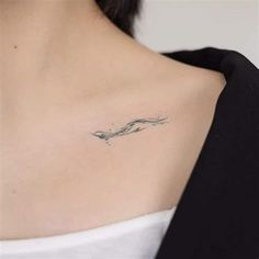 a woman's chest with a small wave tattoo on it