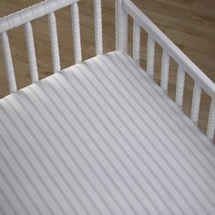 a close up of a white wooden bed frame with striped fabric on the bottom and sides