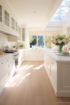 a large kitchen with white cabinets and wooden floors is pictured in this image, there are sun shining through the windows