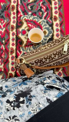 a purse sitting on top of a rug next to a cup of tea