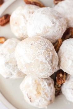 a white plate topped with powdered donuts covered in nuts