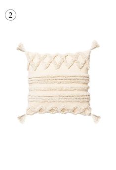 a white pillow with tassels on the front and back, in two different colors