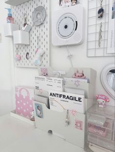 a white desk topped with lots of cards and boxes next to a wall mounted clock