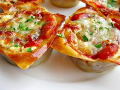 several mini pizzas on a white plate with condiments