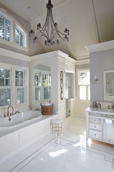 a large white bathroom with a chandelier hanging from the ceiling