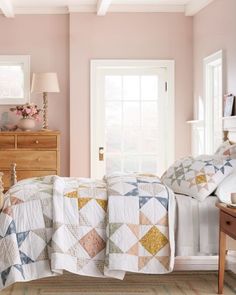 a bedroom with pink walls and quilts on the bedspread, two nightstands and a dresser