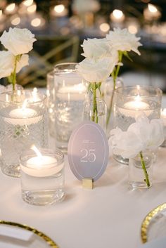 the table is set with candles, flowers and glass vases for guests to sit in