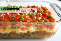 a glass casserole dish filled with beans, tomatoes and green onions on top