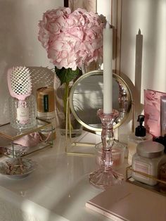 a vanity with pink flowers, candles and other beauty products on top of it next to a mirror