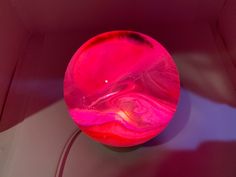 a pink object sitting on top of a white table next to a red light fixture