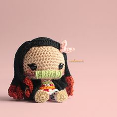 a small crocheted doll sitting on top of a pink background with the word pattern written below it