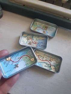 three tins with maps on them sitting on a table