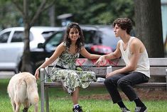 a man and woman sitting on a bench with a dog